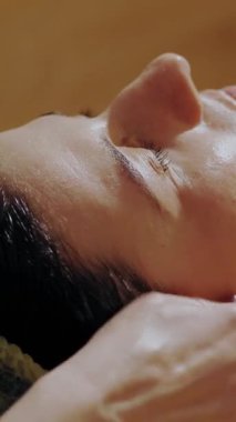 Yaşlanma önleyici prosedür, yüz masajı. Yakın plan. Kadın kanepede uzanıyor ve yüz masajı yaptırıyor. Güzellik kliniğinde yüz ve yüz derisi kanalizasyonu için. Cilt bakımı, kozmetoloji. Kadınlar için kozmetik prosedürleri.