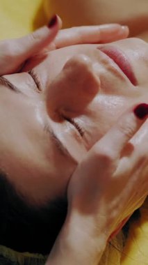 Yaşlanma önleyici prosedür, yüz masajı. Yakın plan. Kadın kanepede uzanıyor ve yüz masajı yaptırıyor. Güzellik kliniğinde yüz ve yüz derisi kanalizasyonu için. Cilt bakımı, kozmetoloji. Kadınlar için kozmetik prosedürleri.