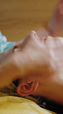 Yaşlanma karşıtı kozmetoloji. Yüz masajı. Yakın plan. Kadın kanepede uzanıyor ve yüz masajı yaptırıyor. Güzellik kliniğinde yüz ve yüz derisi kanalizasyonu için. Cilt bakımı, kadınlar için kozmetik prosedürleri.