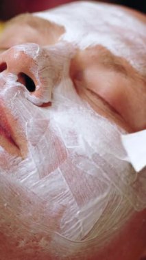 Kozmetoloji, yüz bakımı prosedürleri. Yakın plan. Bir kadının yüzünde altın aljinat kozmetik maske kullanma prosedürü. Yaşlanma karşıtı kozmetikler.