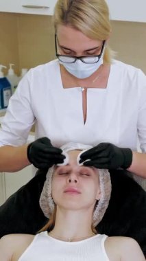 Güzellik iğnesi. Yaşlanma önleyici iğneler. Botulinum terapisi. Yüz tazeleme. Doktor, güzellik enjeksiyonlarından önce hastanın alnını antiseptik pamukla siliyor. Güzellik konsepti.