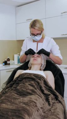 Güzellik iğnesi. Yaşlanma önleyici iğneler. Botulinum terapisi. Yüz tazeleme. Doktor, güzellik enjeksiyonlarından önce hastanın alnını antiseptik pamukla siliyor. Güzellik konsepti.