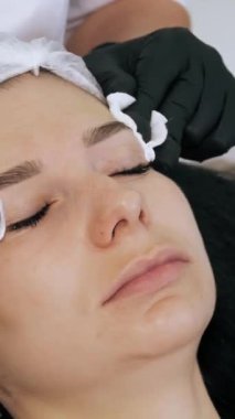 Güzellik iğnesi. Yaşlanma önleyici iğneler. Botulinum terapisi. Yüz tazeleme. Doktor, güzellik enjeksiyonlarından önce hastanın alnını antiseptik pamukla siliyor. Güzellik konsepti.