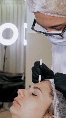 Güzellik iğnesi. Yaşlanma önleyici iğneler. Botulinum terapisi. Yüz tazeleme. Doktor, hastanın alnına güzellik iğneleri için işaretler yapıyor. Kolajen enjeksiyonları. Güzellik konsepti.