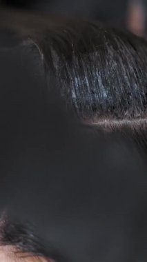 Saç boyama. Saç boyası. Yakın plan. Renkçi usta, kuaförde ya da kuaförde kadın esmer saç köklerine saç fırçasıyla saç boyası uyguluyor..