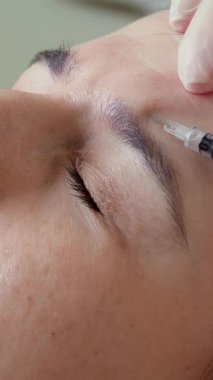 Doktor hastanın alnına güzellik iğneleri yapıyor. Kolajen enjeksiyonları. Yaşlanma önleyici iğneler. Botulin terapisi. Yüz tazeleme.