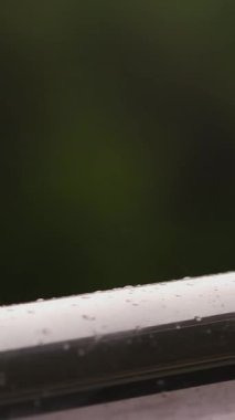 yakın çekim, büyük metal gümüş renk korkuluk üzerine yağmur damlaları. bir arka plan bulanık yeşillik