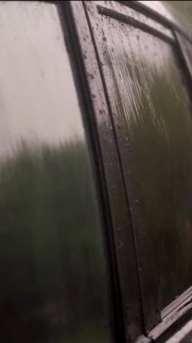 Şiddetli yağmur, duş, damlalar park yerindeki boş siyah arabanın renkli camlarına düşer. Damlacıklar küçük akarsular halinde camdan aşağı akar.