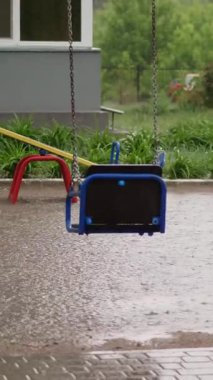 Boş salıncak yağmurda ıslanıyor, rüzgarda sallanıyor. Şiddetli bir yağmur, gök gürültülü bir fırtına güçlü bir rüzgarla sağanak yağış. Bahçede büyük su birikintileri olan bir çocuk parkı var, yaz mevsimi.