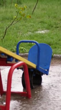 ağır yağmur, güçlü bir rüzgar ile şiddetli bir yağmur altında boş bir oyun alanı. büyük su birikintileri, yaz yağmurlu bir gün