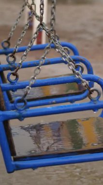 Boş salıncak yağmurda ıslanıyor, rüzgarda sallanıyor. Şiddetli bir yağmur, gök gürültülü bir fırtına güçlü bir rüzgarla sağanak yağış. Bahçede büyük su birikintileri olan bir çocuk parkı var, yaz mevsimi.