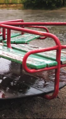 Çocuk parkına yağmur yağıyor. Yakın plan. Islak, boş atlı karınca, bahçede, sağanak yağmur altında dolaşır..