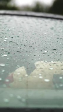 Arabadaki yağmur damlaları. Yağmur. Yağmur yağıyor. Yağmur damlaları arabanın arka camına düşer ve yağmur yağarken yavaşça damlar. yakın plan