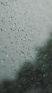 Arabadaki yağmur damlaları. Yağmur. Yağmur yağıyor. Yağmur damlaları yağmur sırasında modern arabanın yan cam yüzeyine düşer ve yavaşça aşağı süzülür. yakın plan