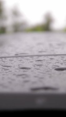 Arabadaki yağmur damlaları. Yağmur. Yağmur yağıyor. Yağmur damlaları damlıyor ve damlıyor, yağmur sırasında modern siyah arabanın çatı yüzeyinden aşağı akıyor. yakın plan.