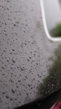 Arabadaki yağmur damlaları. Yağmur. Yağmur yağıyor. Yağmur damlaları modern siyah arabanın yüzeyine düşer ve yağmur sırasında yavaşça damlar, aşağı akar. yakın plan