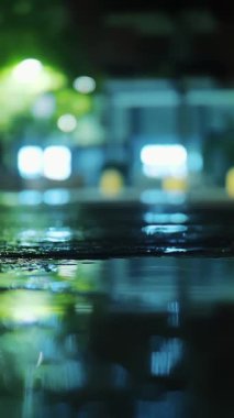 Yağmur. Su birikintisi. Geceleri şehir. Sokak ışıklarıyla yağmur damlası. Yakın plan..