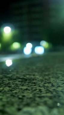 Hafif yağmur. Şehir kaldırımında ışık yansıyan su birikintisi. Sokak lambası. Sokak ışıklarıyla yağmur damlası. Yakın plan..