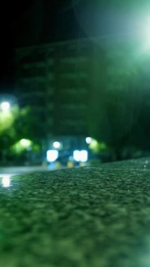 Yağmur. Su birikintisi. Geceleri şehir. Sokak ışıklarıyla yağmur damlası. Yakın plan..