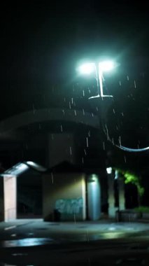 Sokak lambası. Yağmur damlası. Geceleyin yağmur. Hafif yağmur. Şehir kaldırımında ışık yansıyan su birikintisi. Sokak lambası. Sokak Işıklarıyla Yağmur Damlası.