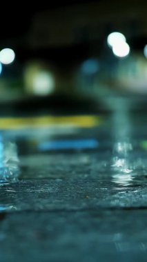 Gece yağmur yağacak. Su birikintisi Sokak lambası. Su birikintisine düşen yağmur damlaları.