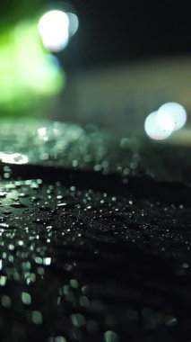 Şehirde yağmur yağıyor. Araba kaputu. Sualtı yolu. İyi geceler. Yağmur damlaları. Yakın plan..