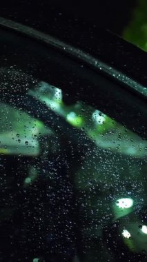 Yağmur damlalarında araba camı. Gece yağmur yağacak. Su birikintisi Sokak lambası. Su birikintisine düşen yağmur damlaları.