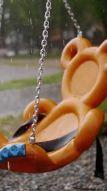 Çocuk parkında Yağmurlu Gün: Yağmur Damlaları ve Su birikintileriyle Çocuk Odağında Sallanma