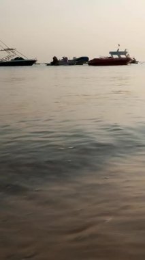 yakın çekim, deniz sörf, gelgit, kum plaj dalgalar deniz. demirli tekneler ve Bay küçük yatlar arasında arka plan üzerine güneş ışınlarının içinde. sıcak yaz günbatımı,