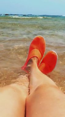 Yakın plan, parlak turuncu su ayakkabılı kadın bacakları, denizde yüzmek için, resiflerde yaralanmamak için. deniz tatili konsepti