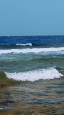 Güzel deniz manzarası. Beyaz köpüklü küçük sörf dalgaları Kızıl Deniz 'in kayalık sahillerinde kırılıyor. Yaz manzaralı deniz manzarası, güneşli sahil manzaralı..