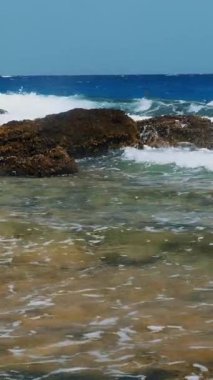 Güzel deniz manzarası. Beyaz köpüklü küçük sörf dalgaları Kızıl Deniz 'in kayalık sahillerinde kırılıyor. Yaz manzaralı deniz manzarası, güneşli sahil manzaralı..