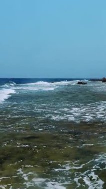 Güzel deniz manzarası. Beyaz köpüklü küçük sörf dalgaları Kızıl Deniz 'in kayalık sahillerinde kırılıyor. Yaz manzaralı deniz manzarası, güneşli sahil manzaralı..