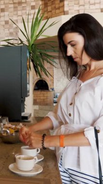 Genç bir kadın açık büfe yemek odasında ya da her şeyi kapsayan bir restoranda paketinden şekeri bardağına boşaltıyor.