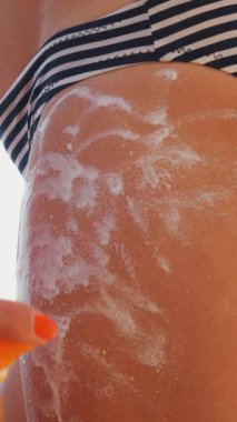 Yakın plan, kadın eli lekesi, çocukların cilt kremi ya da sprey losyonu, plajda, deniz altyapısına karşı. Güneş ve ultraviyole koruma. cilt koruması.