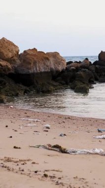 Yakın plan. Çöp, sahildeki çöp. Bir sürü plastik torba, kullanılmış plastik bardaklar ve koruyucu maskeler. Çevre kirliliği kavramı.