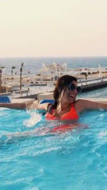 Komik, tıpatıp aynı, yuvarlak güneş gözlüklü kadın, rahatla, lüks otel manzaralı açık havuzda eğlen. Aile tatili kavramı