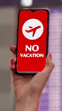 Uçak ikonlu akıllı telefonun yakın plan çekimi, tatil tabelası yok, ekranda, kalkış terminalinde, havaalanındaki uçuş bilgi panosunun önünde..
