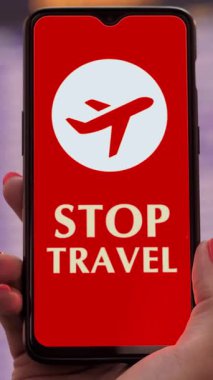 Uçak simgesiyle el ele tutuşan akıllı telefon, ekranda, kalkış terminalinde, havaalanındaki uçuş bilgi panosunun önünde,