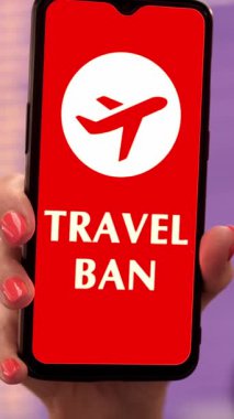 Yaklaş, kadın, koruyucu maskeli, akıllı telefonu uçak ikonu, seyahat yasağı tabelası, ekranda, kalkış terminalinde, havaalanında uçuş bilgi panosunun önünde tutuyor..