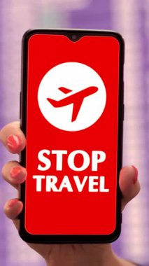 Yaklaş, kadın, koruyucu maskeli, uçak ikonlu akıllı telefon, dur işareti, ekranda, kalkış terminalinde, havaalanında uçuş bilgi panosunun önünde.