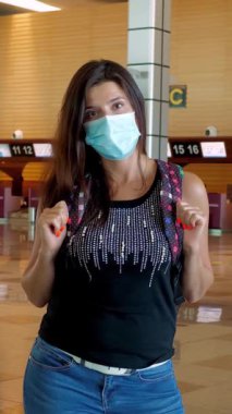 Kadın gezgin, koruyucu maskeli, boş bir havaalanında. Kapalı gişelerin arka planı. Coronavirus salgını sırasında seyahat etmek ya da tecrit