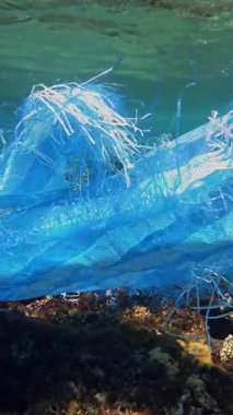 Denizde çöp. Denizin plastik kirliliği. Mavi plastik poşet güneş ışığında yavaşça suyun altında sürükleniyordu. Arka ışıklandırma. Plastik atık çevresel kirlilik sorunu