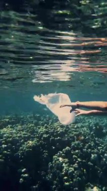 Denizde çöp toplayın. Gönüllü, genç kız, şnorkel maskeli, yüzen çöp topluyor, plastik torba sürüklüyor. Deniz, okyanus kirliliği. çevre koruması.