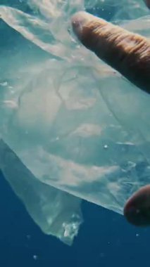 Denizde çöp. Denizi temizle. Sudaki çöpleri toplayın. Yakın plan. Erkek el atıkları yakalar, plastik torbalar kullanır. Birinci şahıs görüşü. Deniz ya da okyanus kirliliği. çevre koruması.