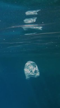 Garbage in the sea. Plastic pollution of the sea. used, white plastic bags slowly drifting, underwater, in the sun lights. Plastic garbage environmental pollution problem