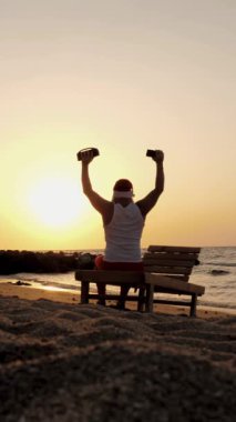 Noel Baba dans ediyor. Komik Noel Baba elinde kablosuz bluetooth hoparlörüyle gün batımına ya da gün doğumuna karşı dans ediyor. Arkadan bak. Kumsalda deniz kenarında rahatla.