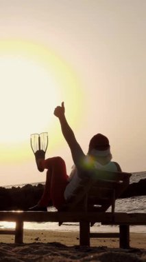 Noel Baba yaz tatili. Noel Baba güneşleniyor. Arkadan bak. Komik Noel Baba, paletlerle, deniz kıyısında uzanır ve gün batımının ya da güneşin doğuşunun tadını çıkarır, dinlenir. Deniz kıyısında..