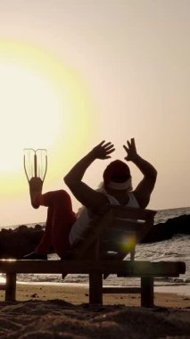 Noel Baba yaz tatili. Noel Baba güneşleniyor. Arkadan bak. Komik Noel Baba, paletlerle, deniz kıyısında uzanır ve gün batımının ya da güneşin doğuşunun tadını çıkarır, dinlenir. Deniz kıyısında..