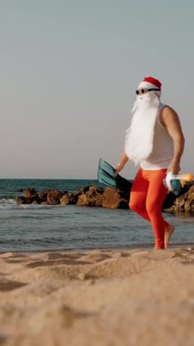 Noel Baba yaz tatili. Noel Baba eğleniyor. Güneş gözlüklü, yüzgeçli ve şnorkelli komik Noel Baba deniz sahilinde koşar. Yüzmek için acele ediyor, şnorkel..